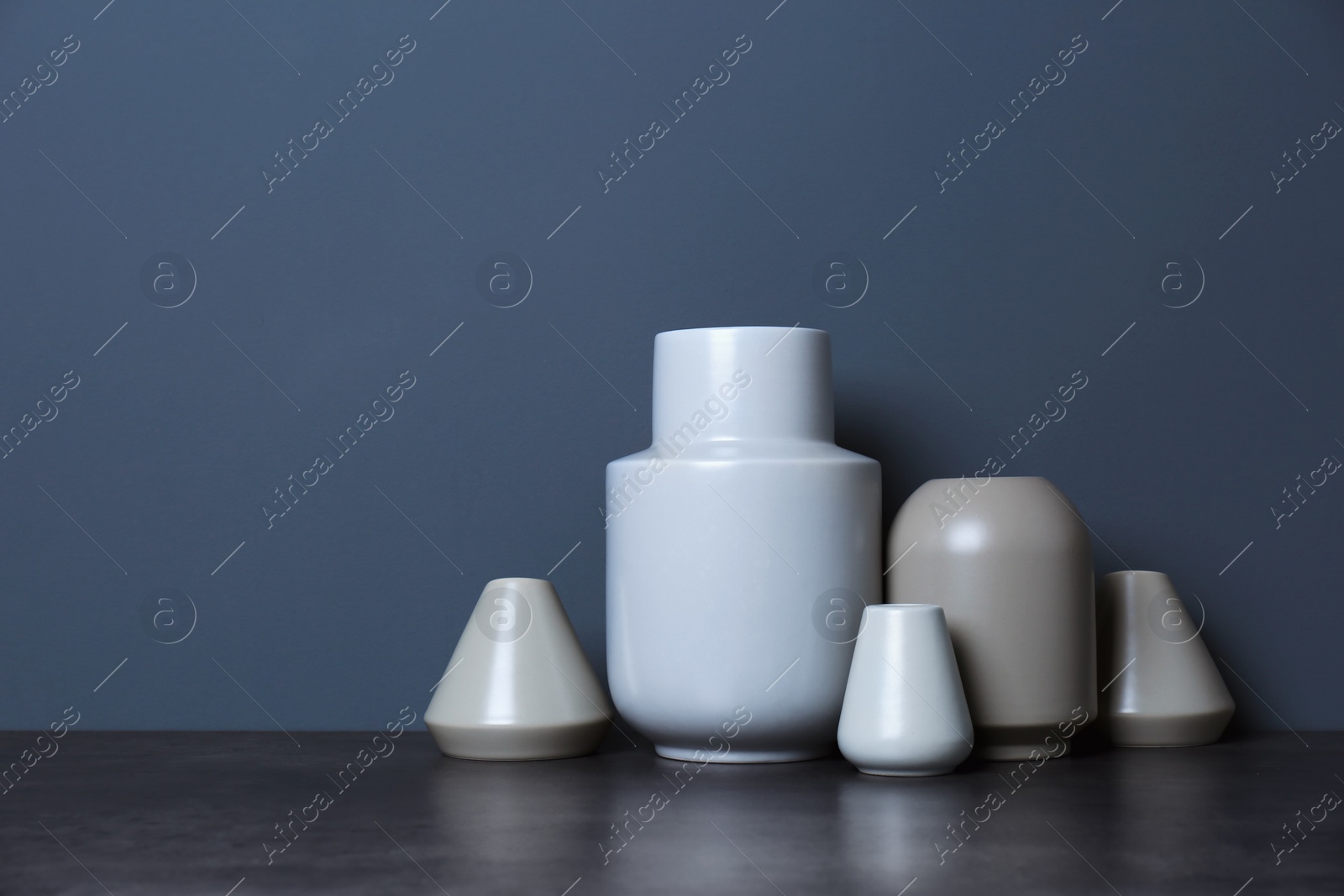 Photo of Beautiful ceramic vases on table against color wall with space for text