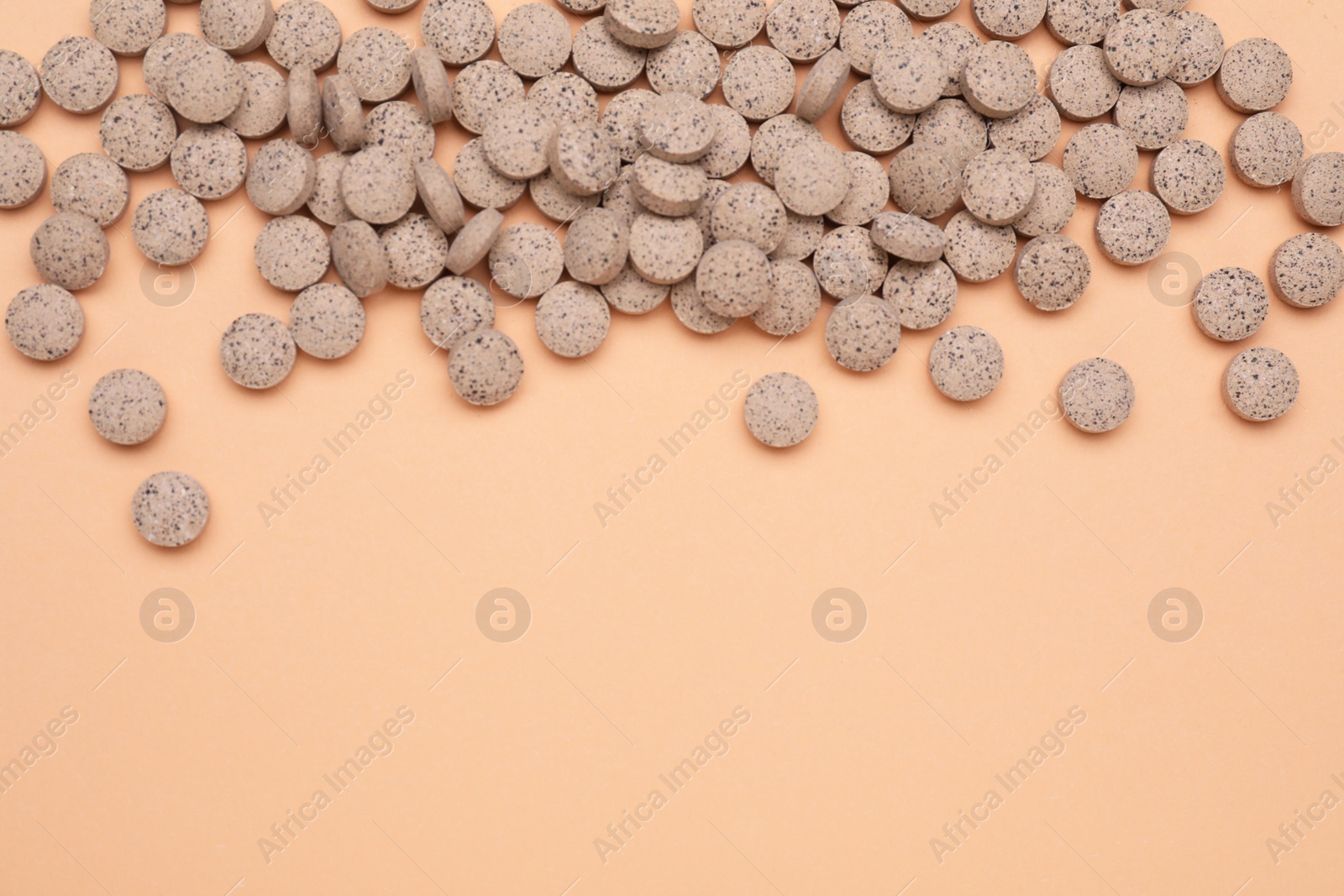 Photo of Beer yeast pills on pale orange background, flat lay. Space for text