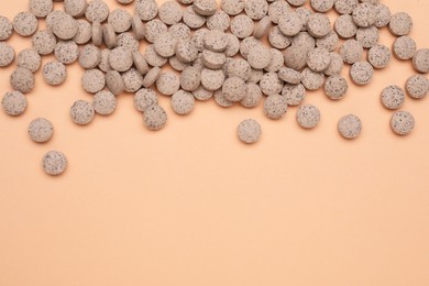 Photo of Beer yeast pills on pale orange background, flat lay. Space for text