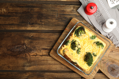 Photo of Tasty broccoli casserole in baking dish on wooden table, flat lay. Space for text