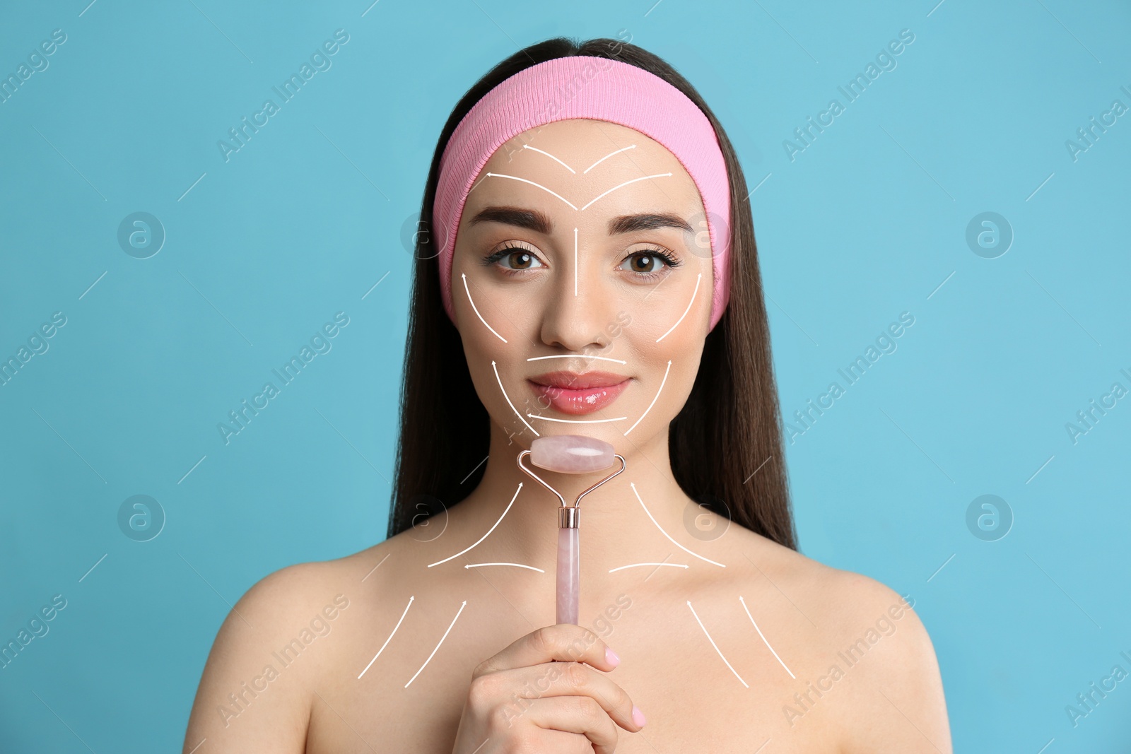 Image of Woman using natural face pink quartz roller on light blue background