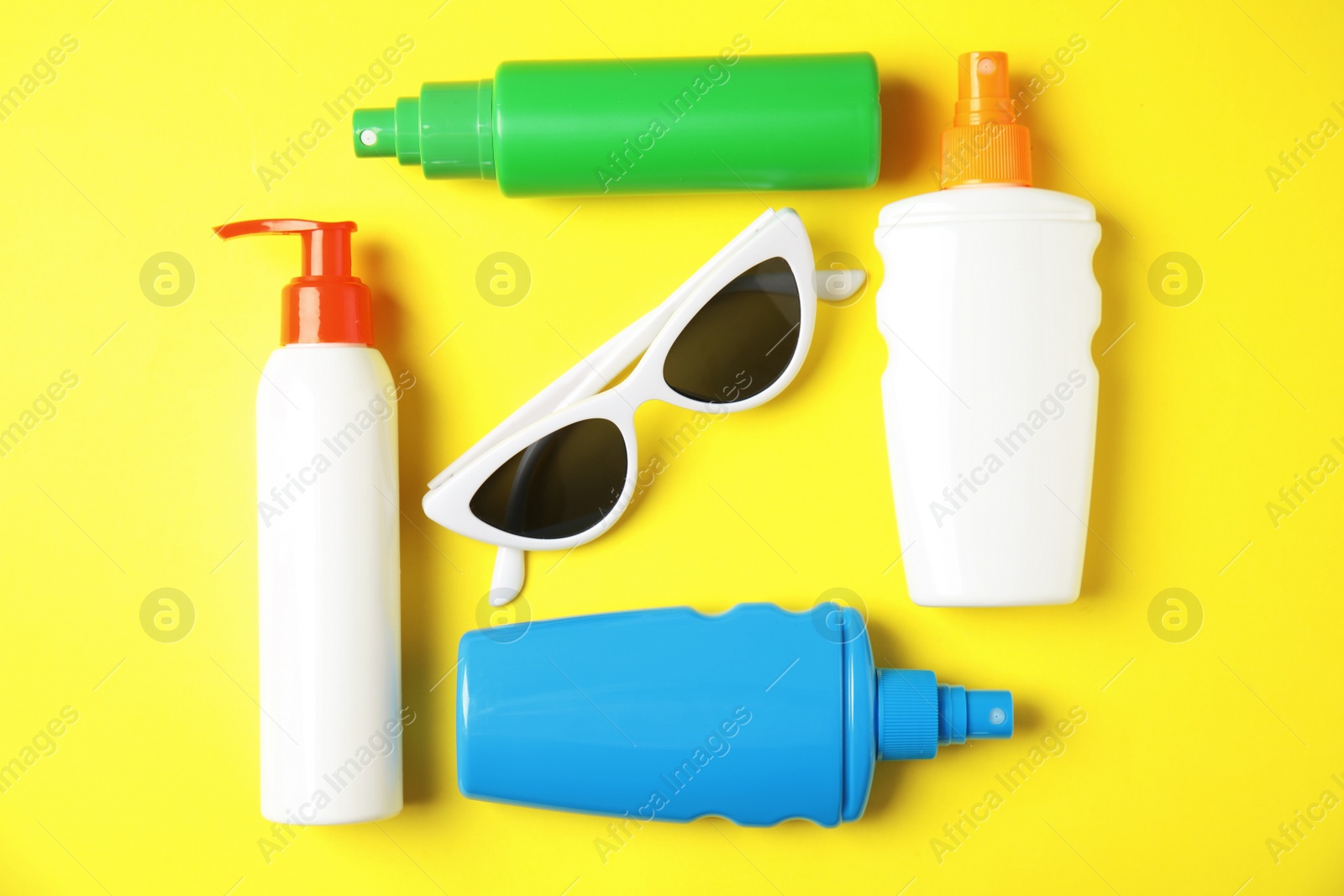 Photo of Flat lay composition with sun protection products and glasses on color background