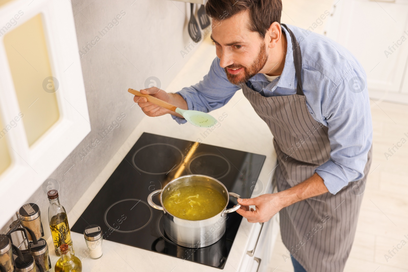 Photo of Man cooking delicious chicken soup in kitchen, above view