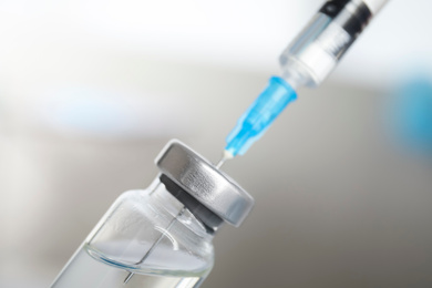 Photo of Vial and syringe on blurred background. Vaccination and immunization