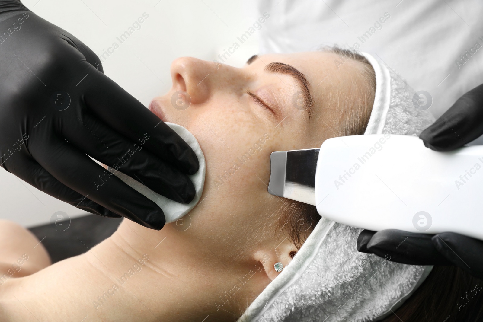 Photo of Cosmetologist using ultrasonic scrubber, closeup. Client having cleansing procedure indoors