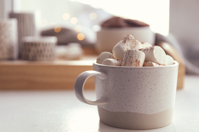 Cup of delicious hot cocoa with marshmallows on white table indoors. Winter drink