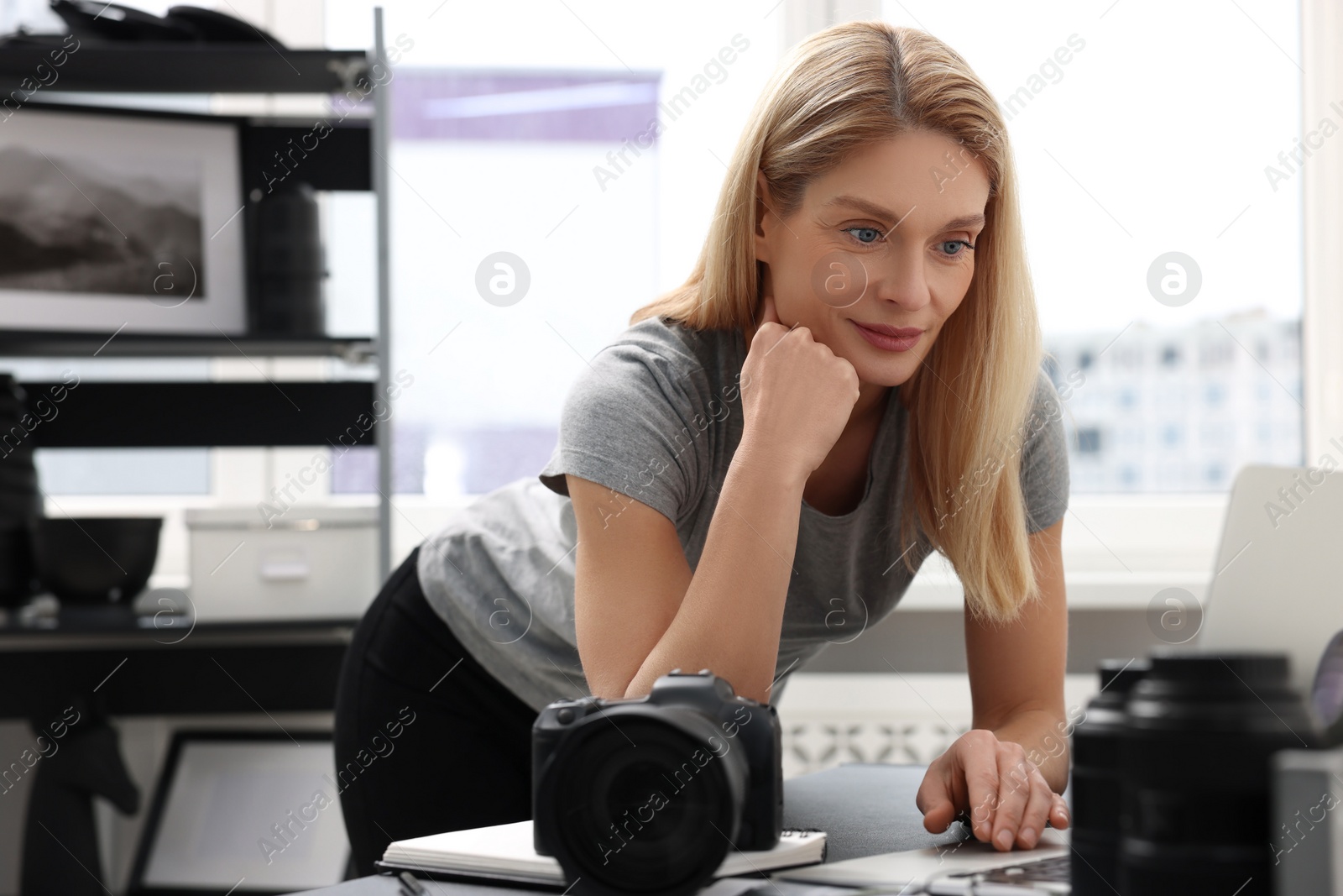 Photo of Professional photographer with digital camera at table in office