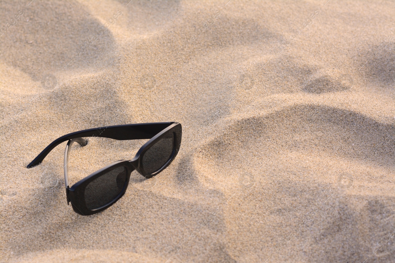 Photo of Stylish sunglasses on sandy beach, space for text