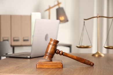 Photo of Law concept. Gavel, scales and laptop on wooden table in office