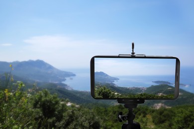 Image of Taking photo of beautiful mountain landscape with smartphone mounted on tripod