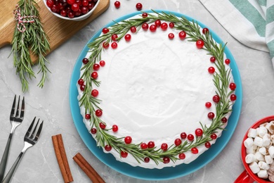 Photo of Traditional Christmas cake decorated with rosemary and cranberries on light grey marble table, flat lay