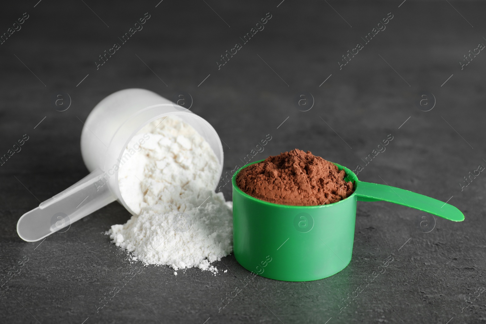 Photo of Scoops of different protein powders on grey background