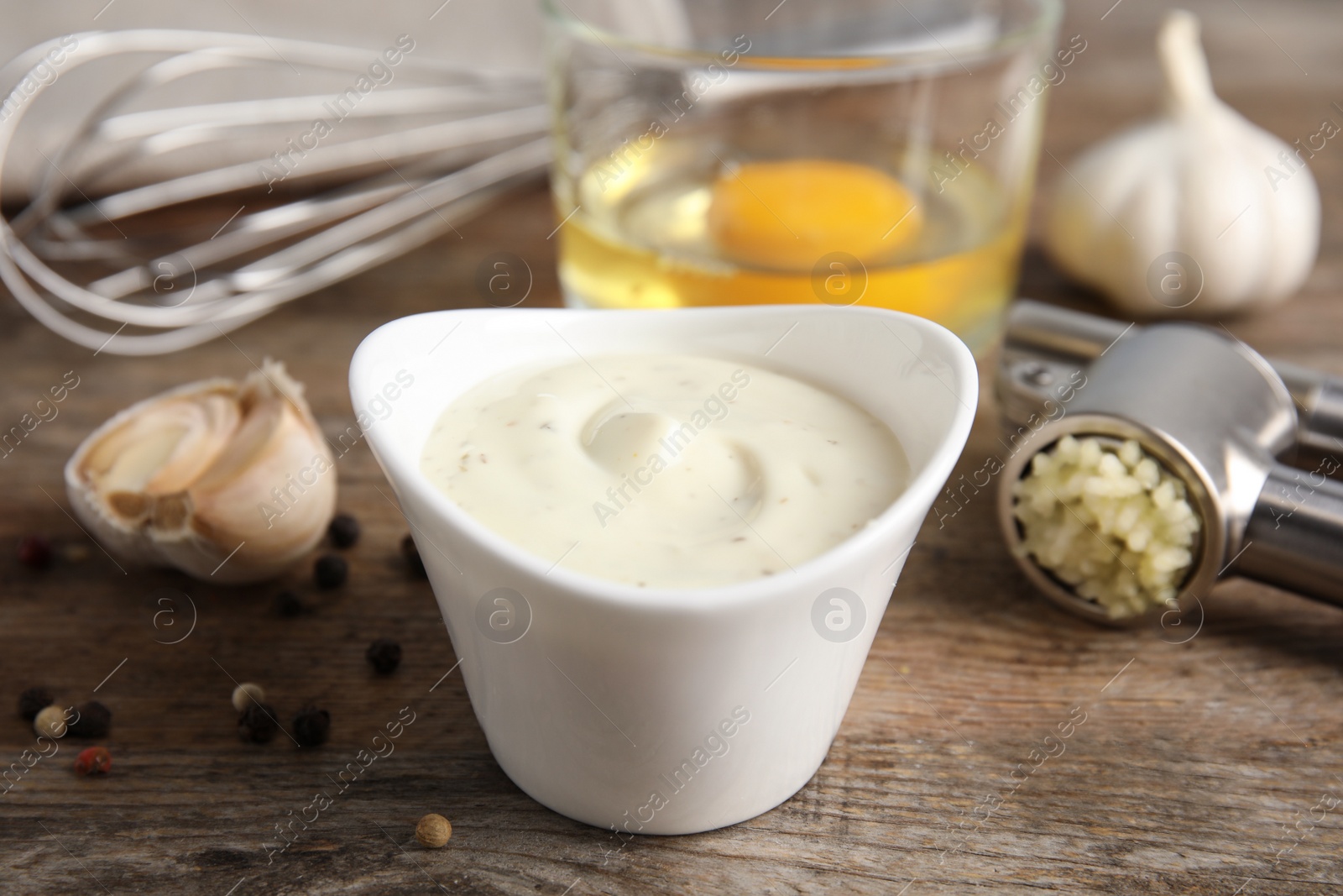 Photo of Composition with bowl of garlic sauce on wooden table