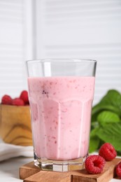 Photo of Tasty raspberry smoothie in glass on white table, closeup