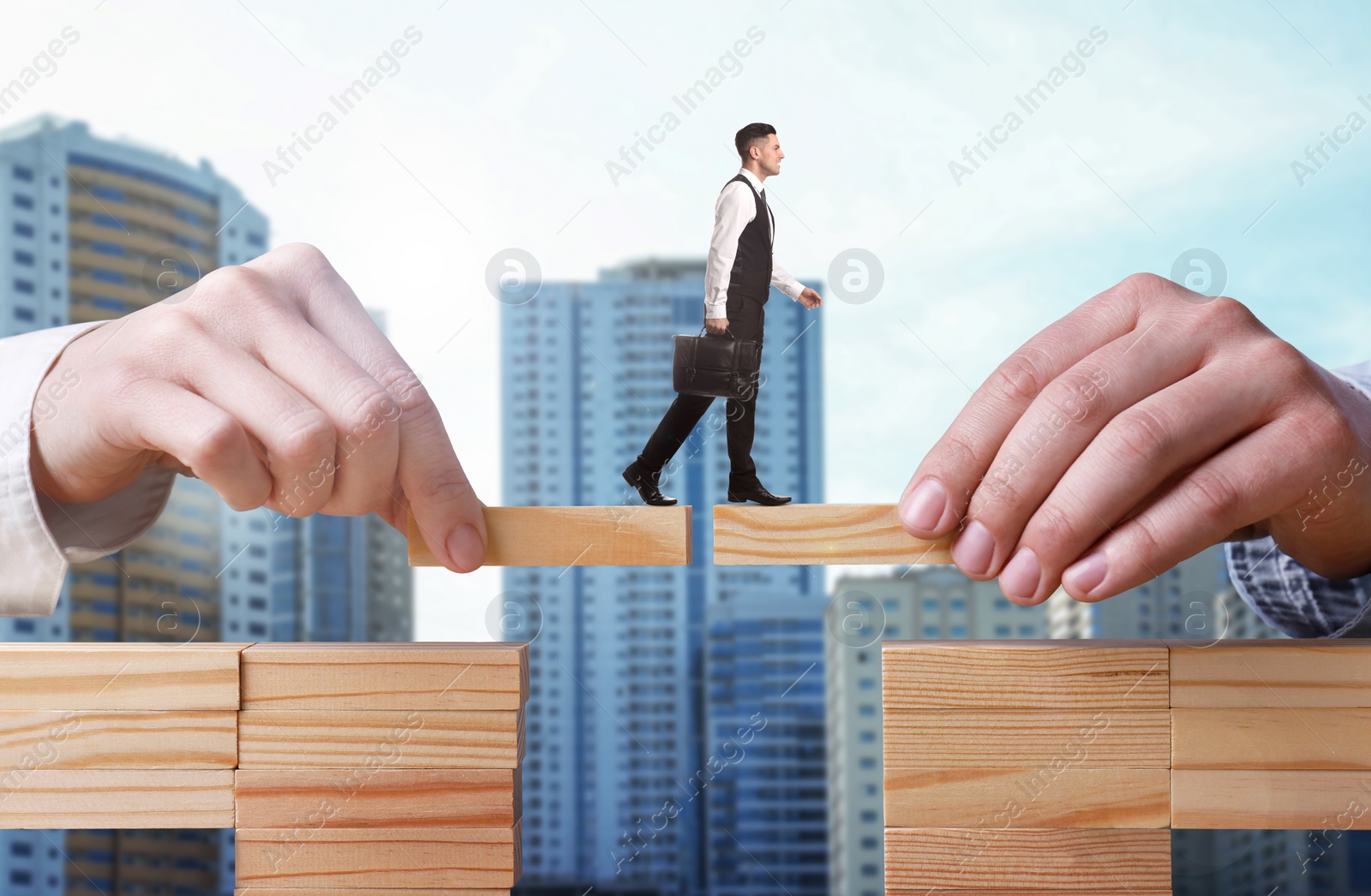 Image of Support or partnership concept. People making bridge of wooden blocks to help businessman walk forward. Blurred cityscape on background