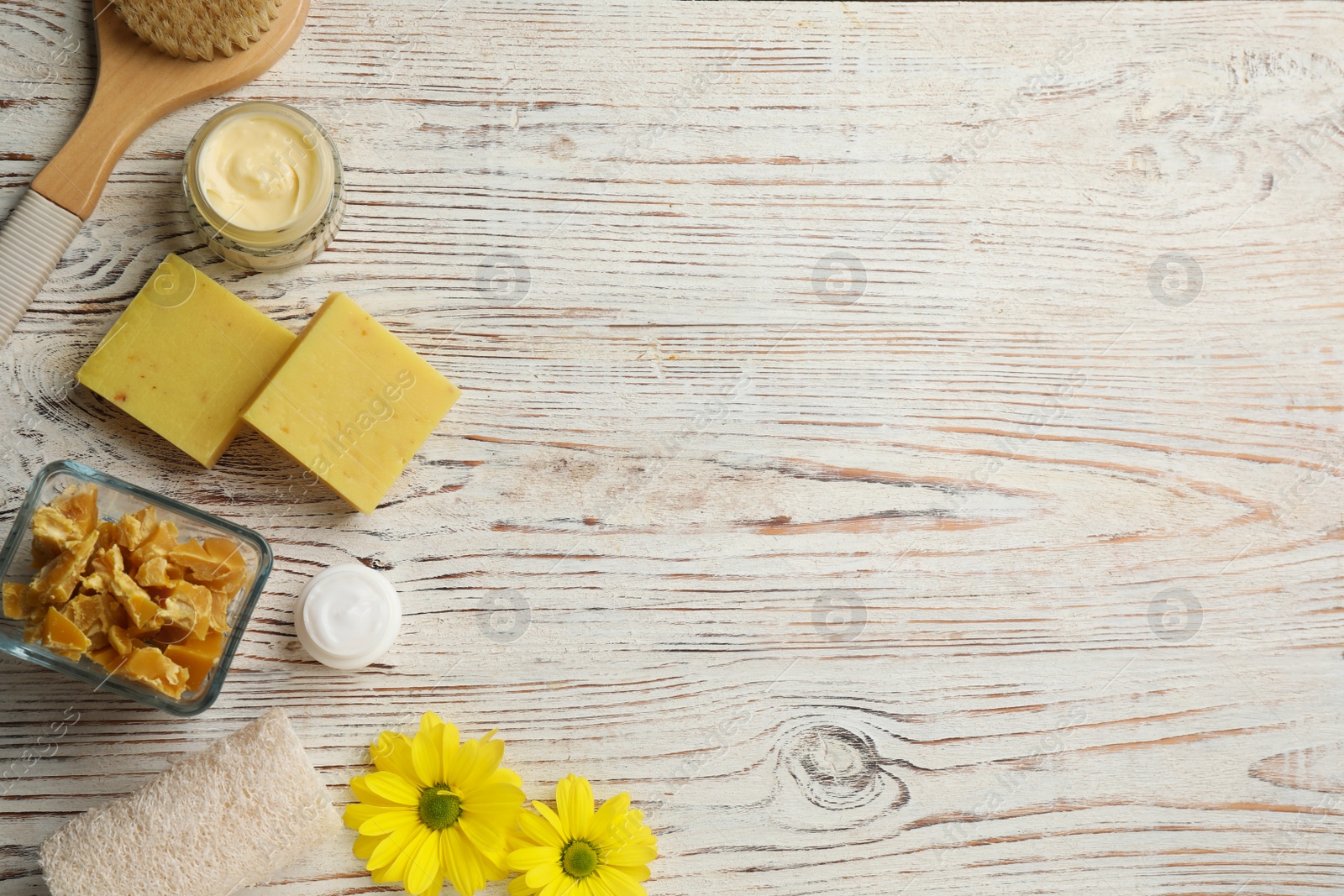 Photo of Flat lay composition with beeswax and cosmetic products on white wooden table. Space for text