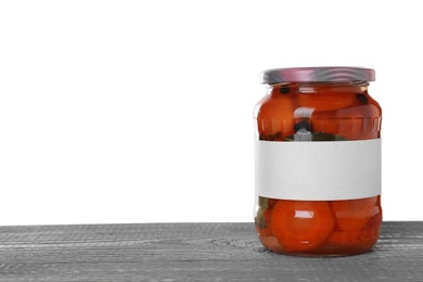 Photo of Jar of pickled sliced carrots with blank label on blue wooden table against white background. Space for text