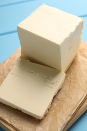 Photo of Block of tasty butter on light blue wooden table