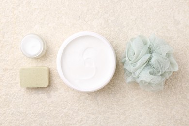 Composition with body care cream in open jars and soap bar on light textured table, flat lay