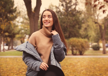 Young woman wearing stylish clothes in autumn park, space for text