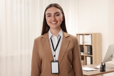 Happy woman with blank badge in office