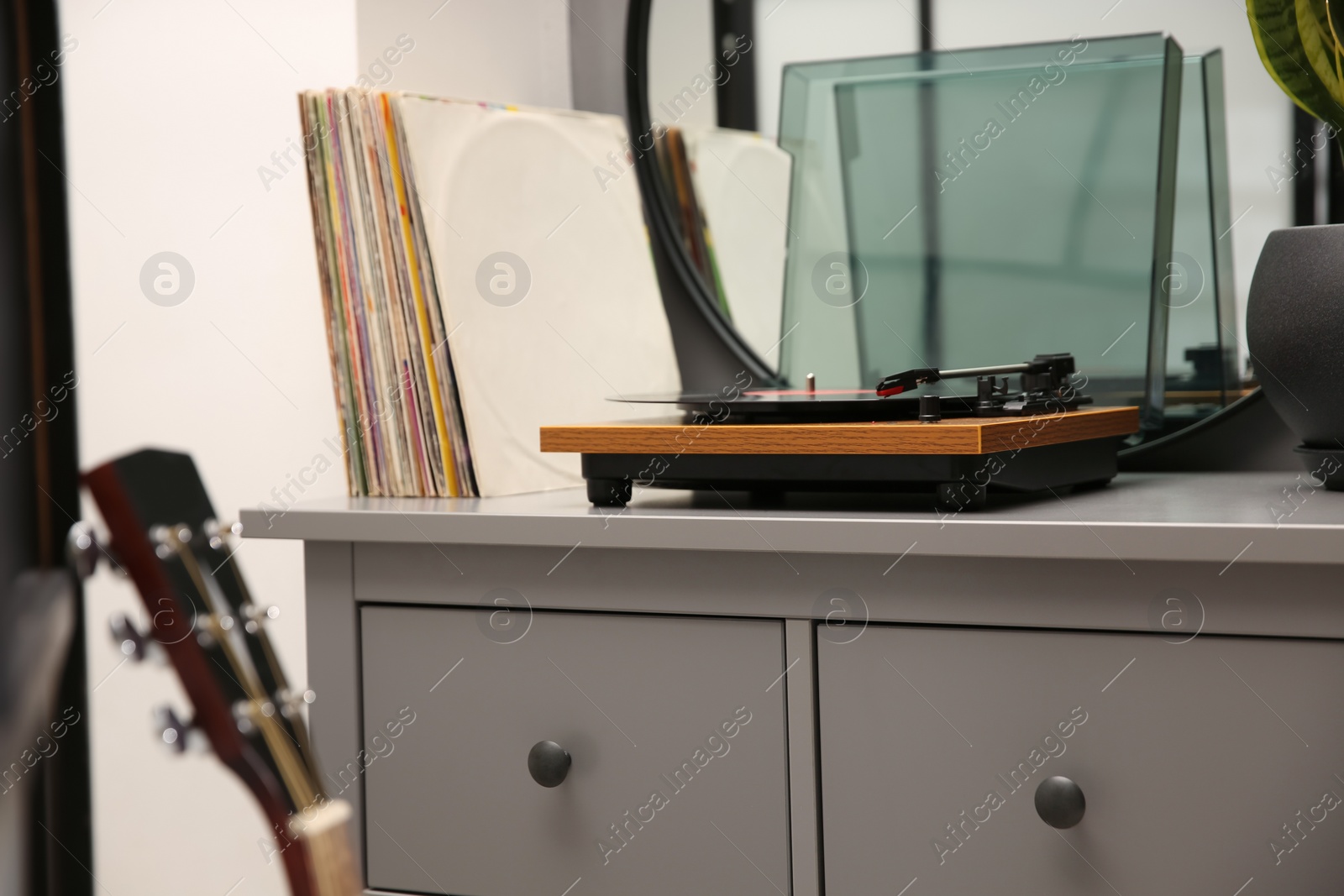 Photo of Stylish turntable with vinyl record on chest of drawers indoors