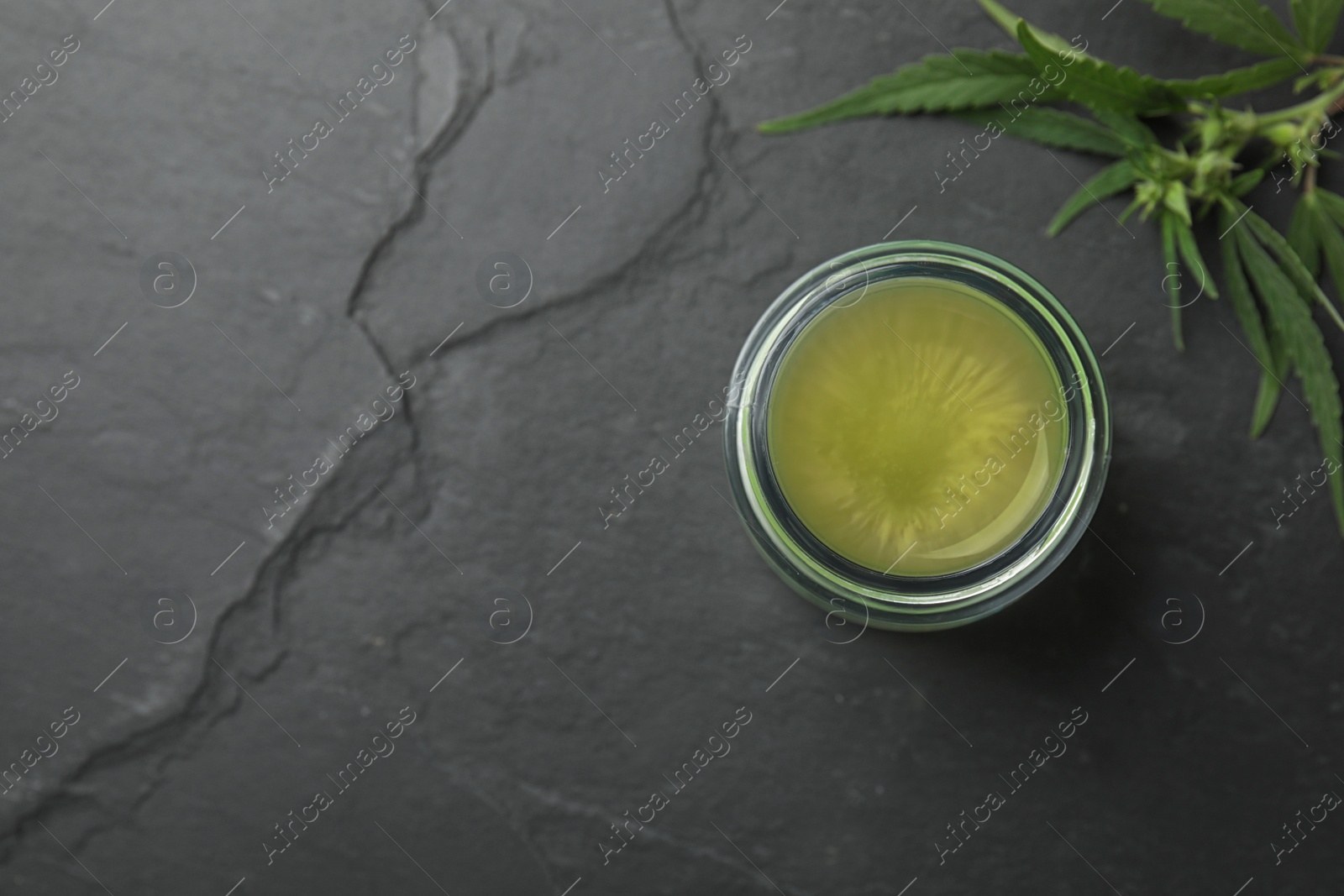 Photo of Jar of hemp cream on dark stone table, flat lay with space for text. Organic cosmetics