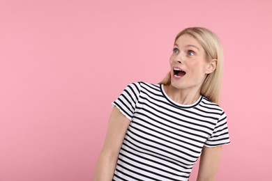 Portrait of surprised woman on pink background, space for text