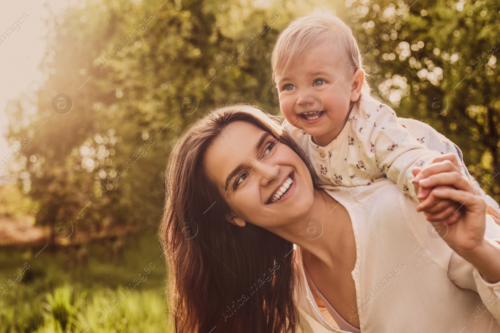 Image of Happy mother playing with her cute baby in park on sunny day