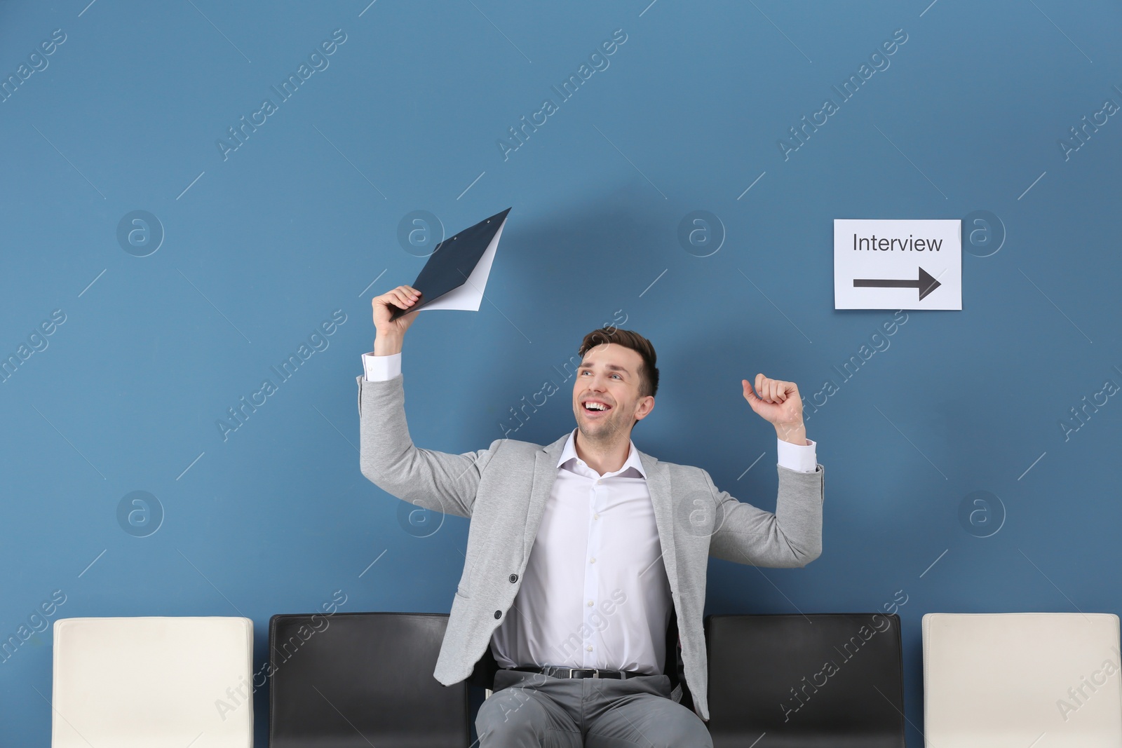 Photo of Young man being happy after success job interview, indoors