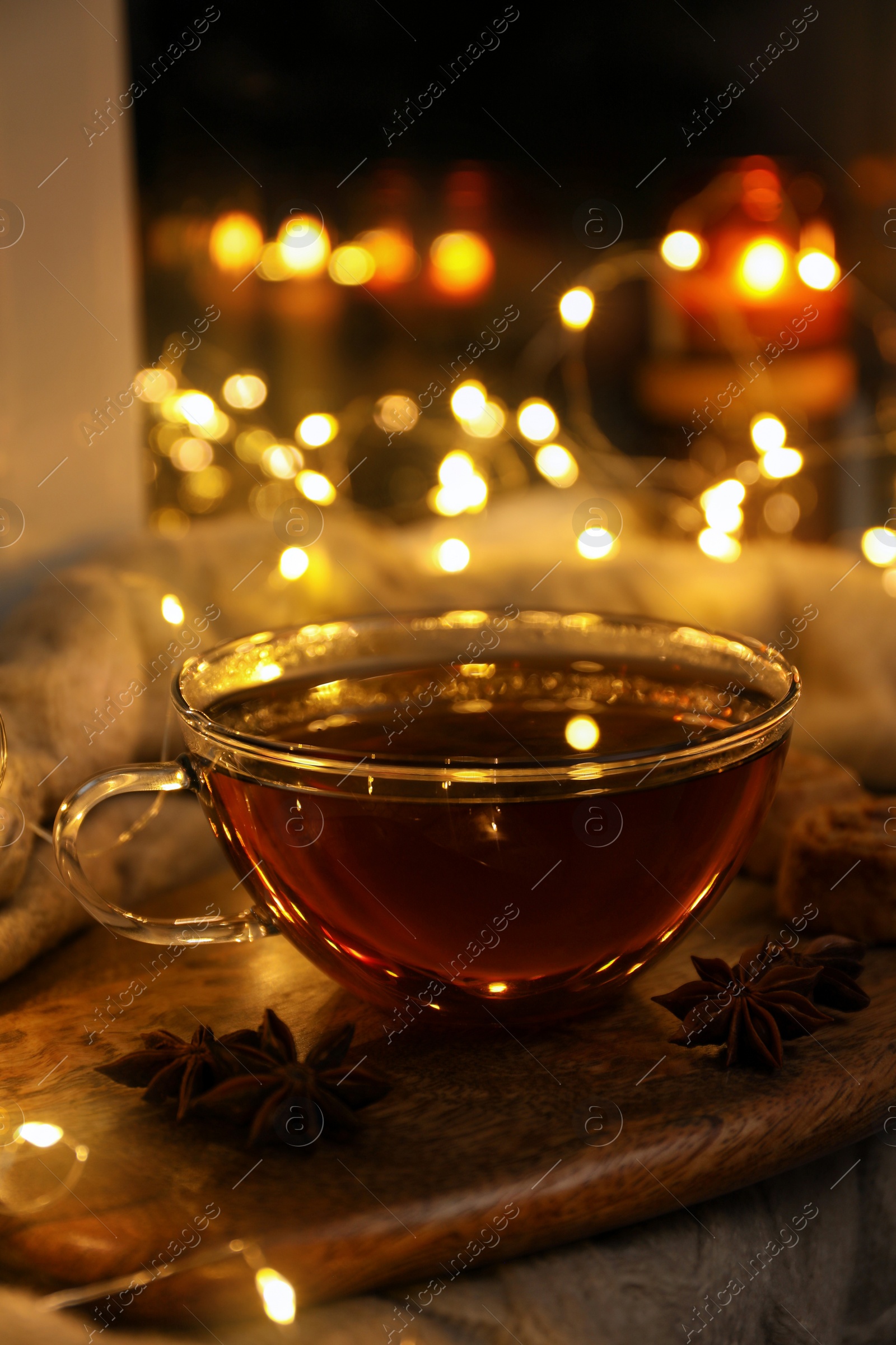 Photo of Glass cup of aromatic anise tea on wooden board indoors, bokeh effect