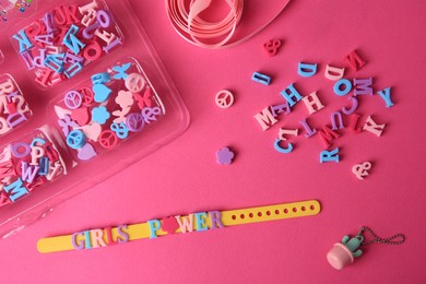 Photo of Handmade jewelry kit for kids. Colorful beads, ribbon and bracelet on bright pink background, flat lay