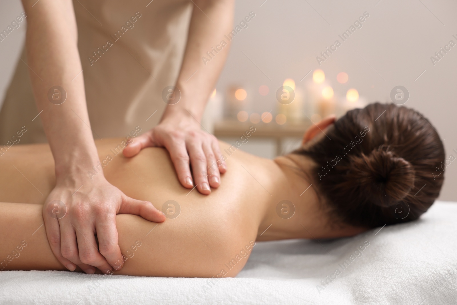 Photo of Woman receiving back massage on couch in spa salon