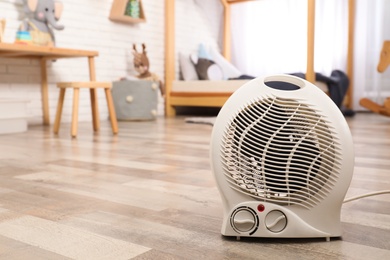 Photo of Modern electric fan heater on floor at home. Space for text