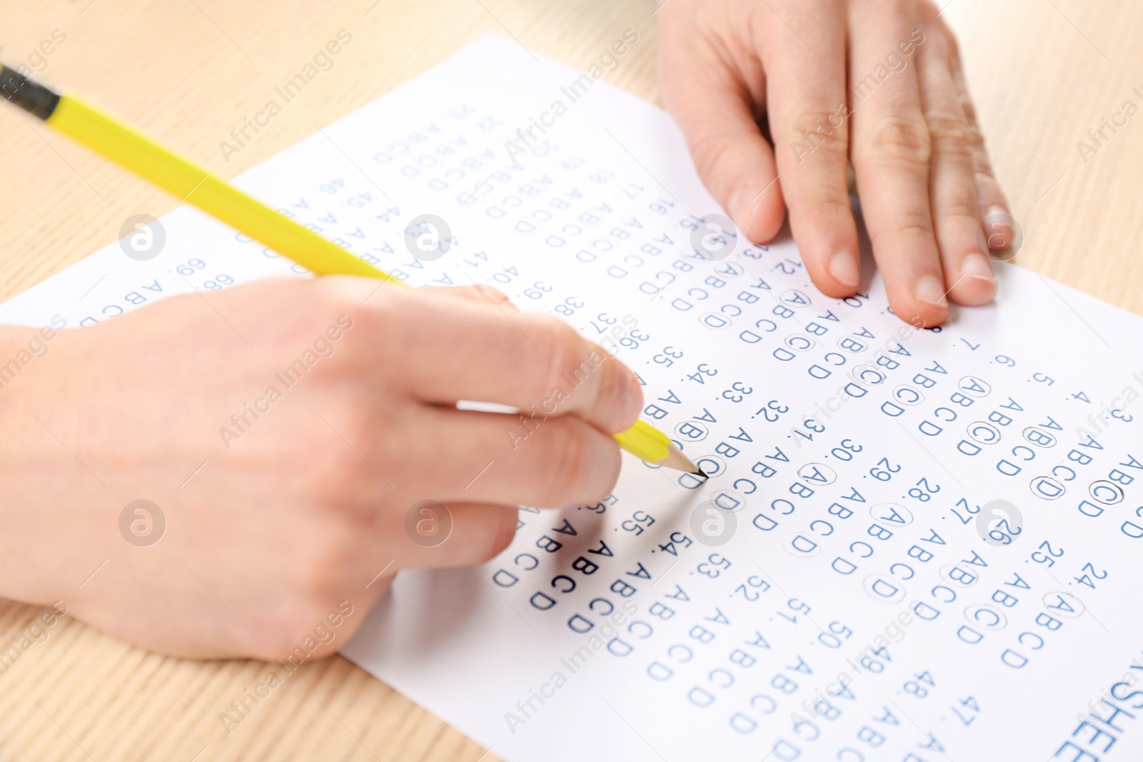 Photo of Student filling answer sheet at table, closeup