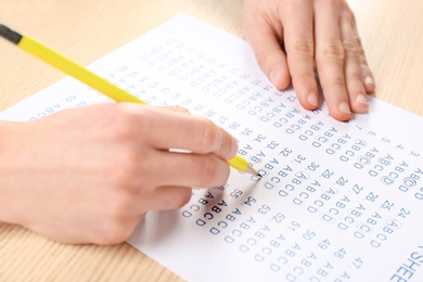 Student filling answer sheet at table, closeup