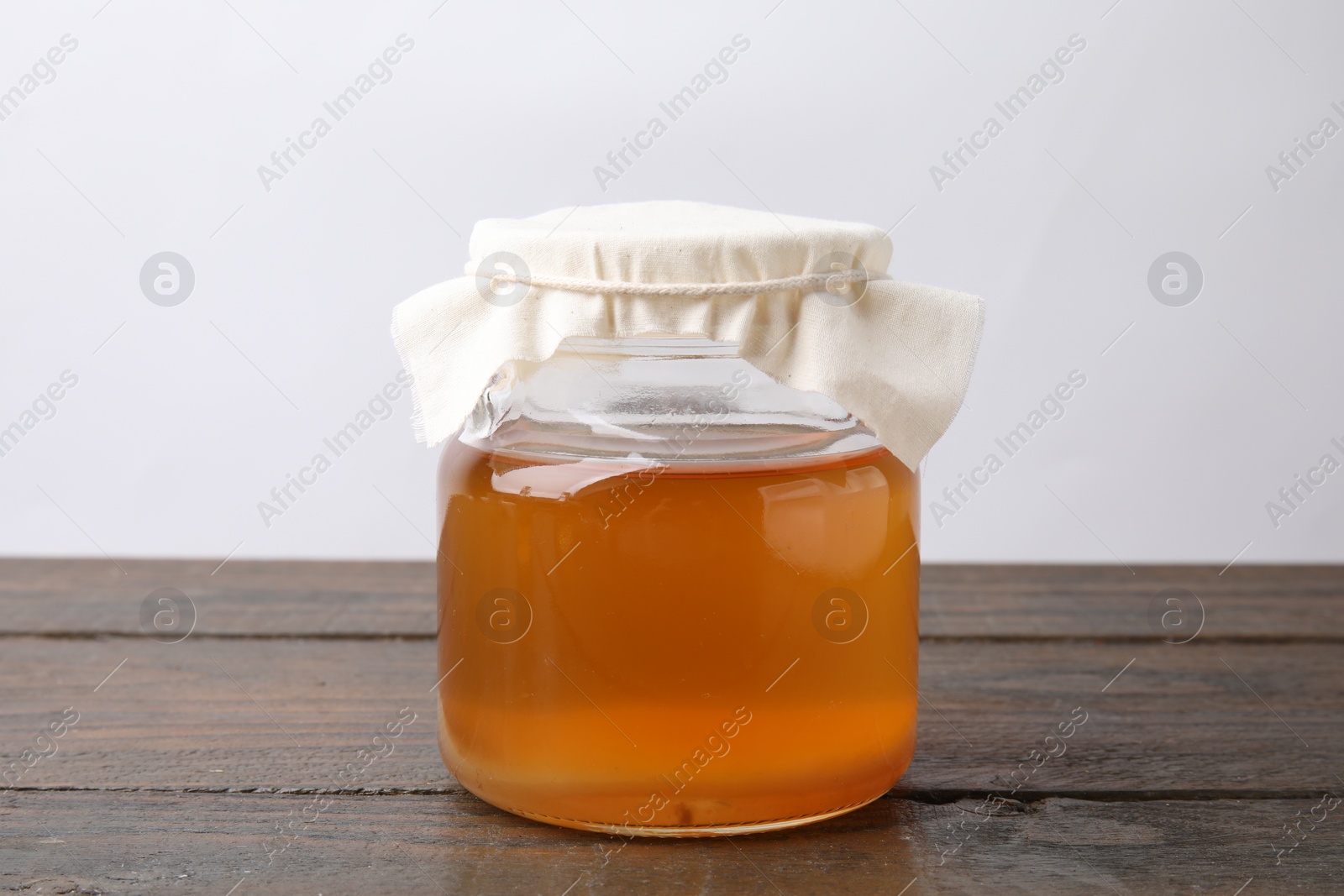 Photo of Homemade fermented kombucha in glass jar on wooden table