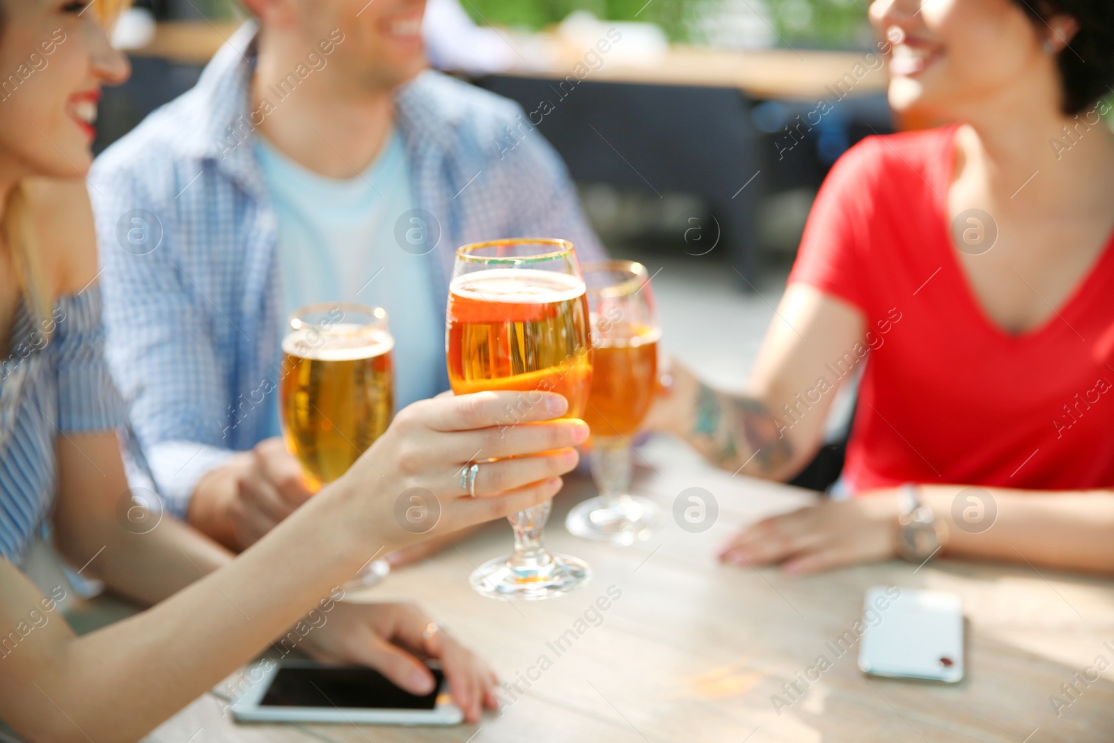 Photo of Young people with glasses of cold beer at table