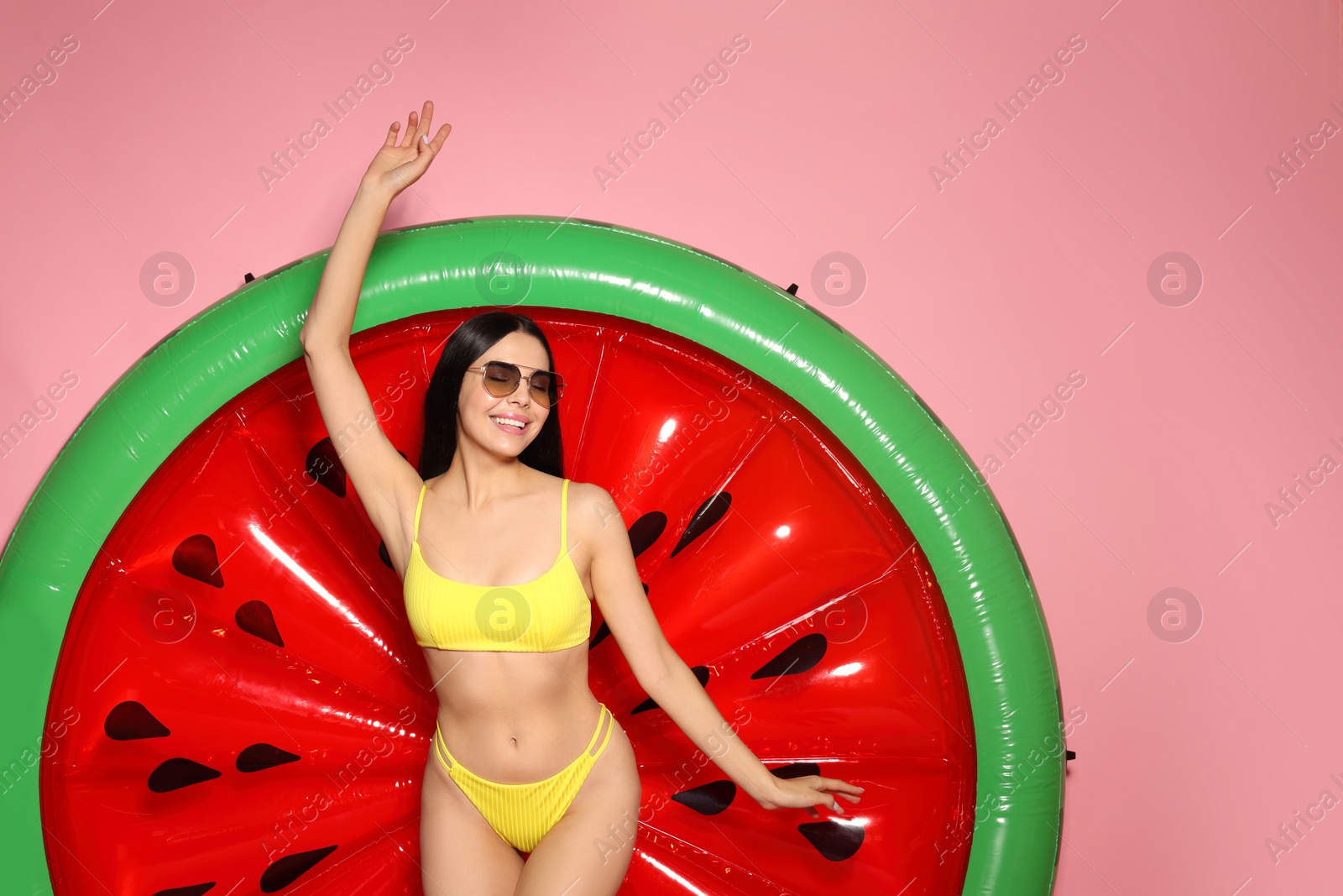 Photo of Young woman with stylish sunglasses near inflatable mattress against pink background