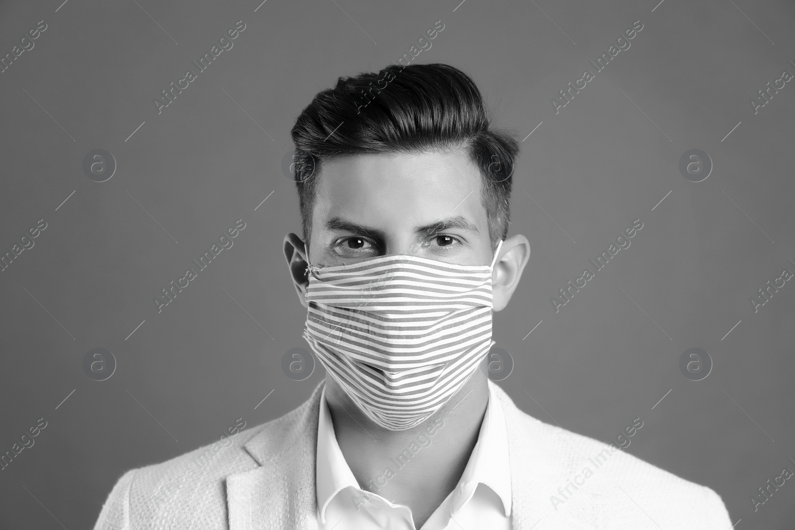 Image of Man wearing medical face mask on grey background. Black and white photography
