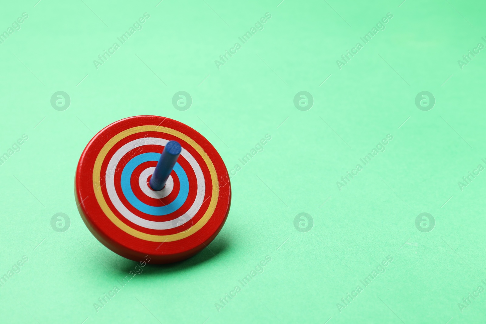 Photo of One bright spinning top on aquamarine background, space for text