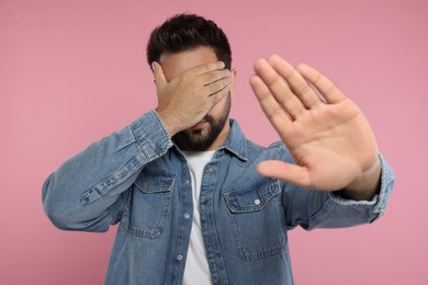 Photo of Embarrassed man covering face with hand on pink background