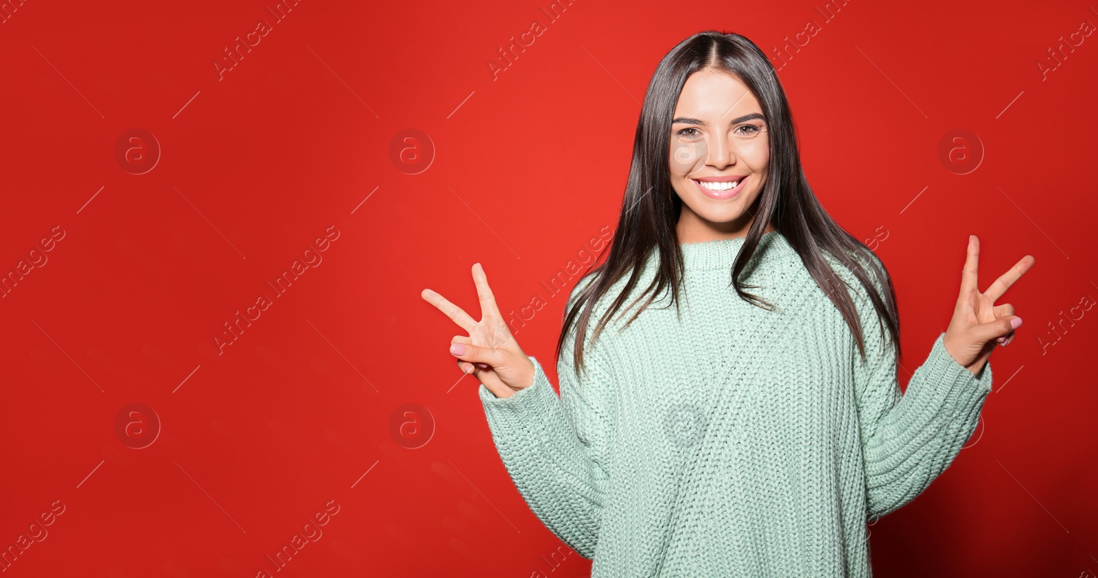 Photo of Young woman in warm sweater on red background