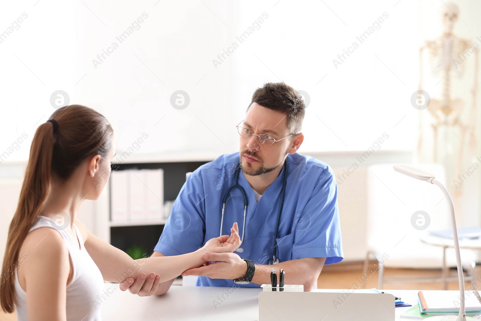 Photo of Male orthopedist examining patient's arm in clinic