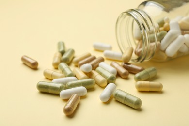 Photo of Vitamin pills and bottle on beige background, closeup