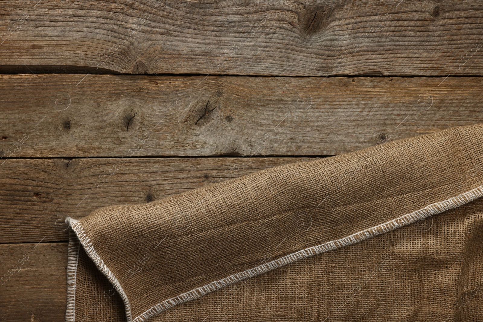 Photo of Burlap fabric on wooden table, top view. Space for text