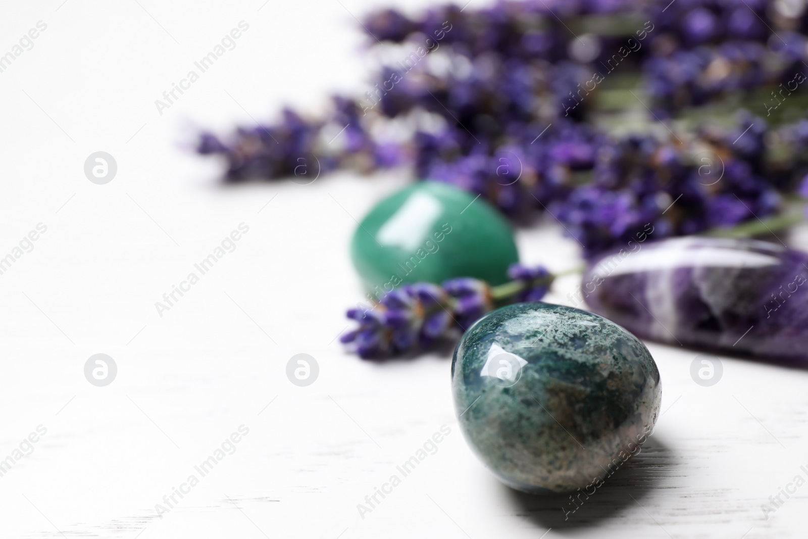 Photo of Gemstones and healing herbs on white wooden table, closeup. Space for text