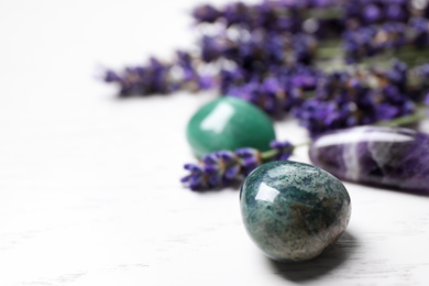Photo of Gemstones and healing herbs on white wooden table, closeup. Space for text