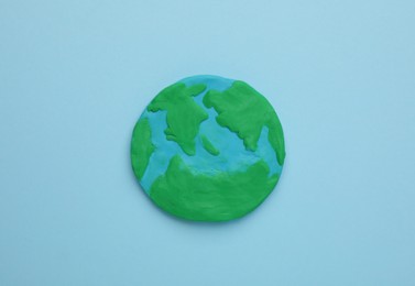 Photo of Plasticine model of planet on light blue background, top view. Earth Day