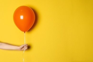 Photo of Woman holding orange balloon on color background